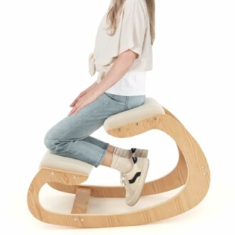 Woman sitting on an ergonomic kneeling chair with wooden frame.