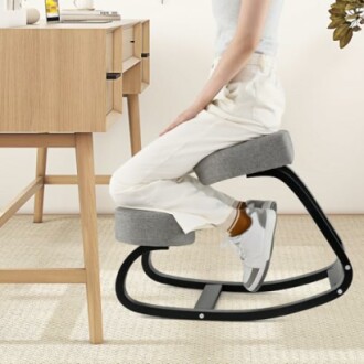 Person sitting on an ergonomic kneeling chair at a desk.
